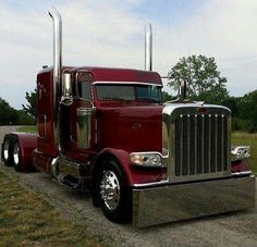 a red semi truck parked on the side of a road