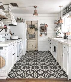 an instagramted photo of a kitchen with white cabinets and black tile flooring