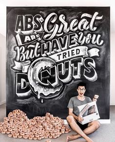 a man sitting on the floor in front of a chalkboard with doughnuts