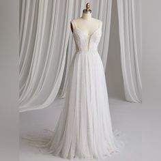 a white wedding dress on a mannequin in front of curtained drapes