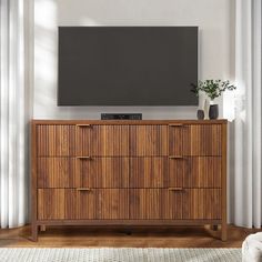 a flat screen tv mounted on top of a wooden dresser