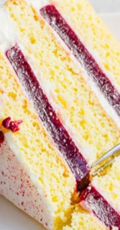 a piece of cake with white frosting and raspberry sauce being cut by a knife