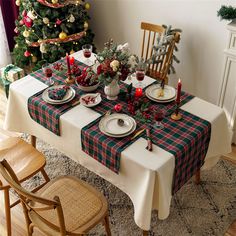 a table set for christmas dinner in front of a tree