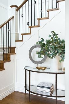 there is a vase with flowers on the table next to the stair case in this room