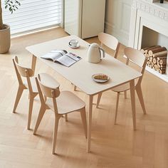 a dining table with four chairs and a book on it in front of a fireplace