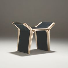 a black and gold side table sitting on top of a white floor next to a gray wall