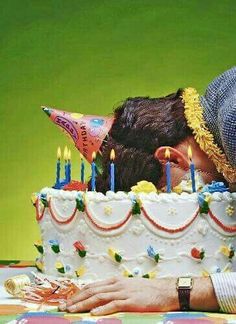 two people kissing in front of a birthday cake with candles on it and one person leaning over the cake