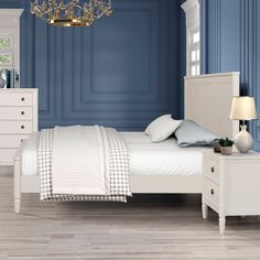 a bedroom with blue walls, white furniture and a chandelier hanging from the ceiling