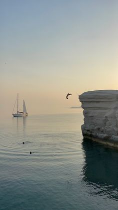 a sailboat is in the water near an iceberg