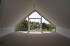 an empty room with a large window in the center and trees out to the side