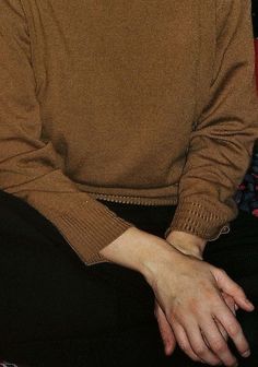 a man sitting down wearing a brown sweater