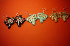 three pairs of earrings are sitting on a red surface, one is black and the other is green