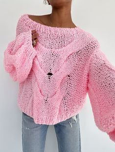 a woman is wearing a pink sweater with holes in the front and bottom, she has her hands on her hips