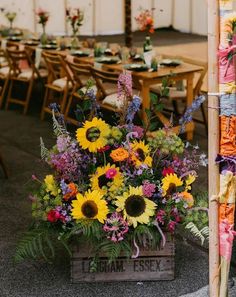 a wooden crate filled with lots of flowers on top of a floor next to tables