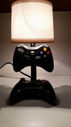 a lamp that is sitting on top of a table with a video game controller in front of it