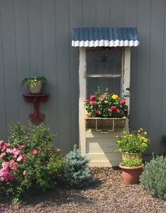 an old window is filled with potted flowers and other greenery in front of the house