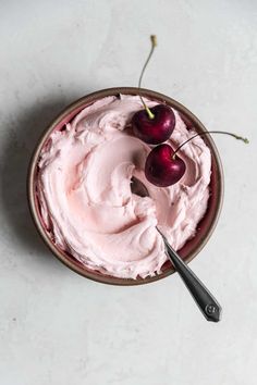 a bowl filled with whipped cream and two cherries