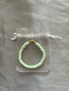 a green and white beaded bracelet on a clear plastic bag