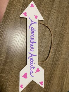 a wooden sign that says congratulations and an arrow with pink hearts on it sitting on top of a table