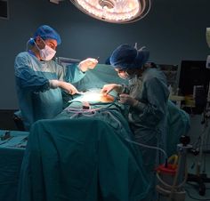 two doctors performing surgery on a patient in an operating room with lights above their heads