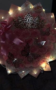 a tiara with pink roses and butterflies on it, surrounded by fairy light garlands