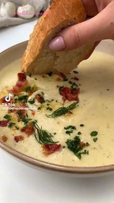 a person dipping some bread into a bowl of soup