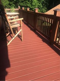 a wooden deck with chairs on it and trees in the background