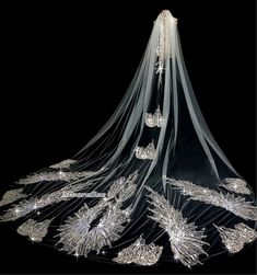 an elaborate wedding veil with crystal beads and pearls on the bottom, hanging from a black background