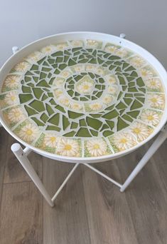 a white table topped with a green and yellow mosaic design on top of a wooden floor