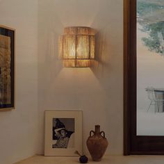 a lamp that is on the side of a wall next to a vase and pictures