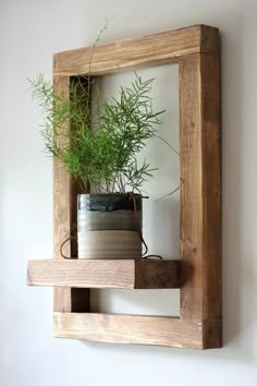 a potted plant in a wooden frame mounted on the wall above a shelf with two books