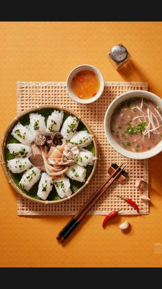 there is a bowl of food and two bowls of soup on the table with chopsticks