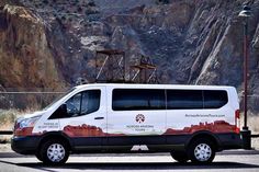 a white van parked in front of a mountain with a tower on it's roof