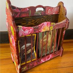 a wooden magazine rack with magazines in it on a wood floor next to a wall