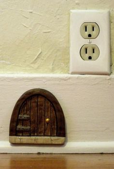 an electrical outlet with two plugs and a wooden door on the wall next to it