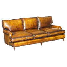 a brown leather couch sitting on top of a white floor next to a wooden frame