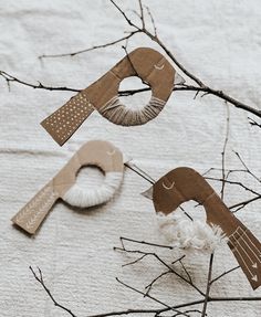 some paper birds are hanging from branches on the snow covered ground, and one bird is made out of cardboard