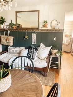 a living room filled with lots of furniture next to a wooden table and chair in front of a mirror