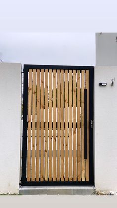 a cat sitting on the ground in front of a wooden gate with bars attached to it