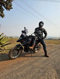 a man is sitting on his motorcycle in the dirt