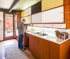 a man standing in a kitchen next to a sink