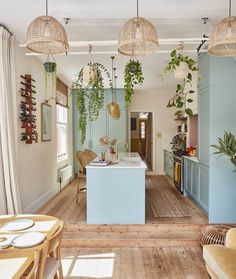 an open kitchen and dining area with plants hanging from the ceiling, along with wicker chairs