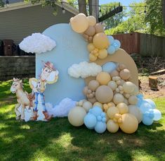 an outdoor birthday party with balloons on the grass and decorations in the shape of clouds