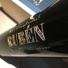 a close up view of the logo on a black baseball bat with books in the background