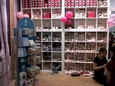 two people sitting on the floor in front of some shelves with balloons and other items