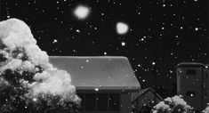 a black and white photo of snow falling from the sky in front of a house