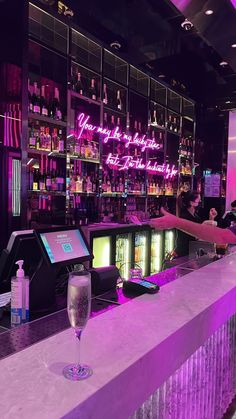 a bar with purple lighting and liquor bottles