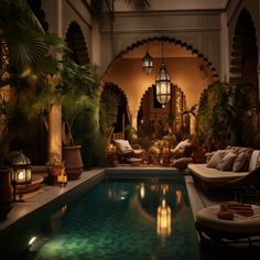 an indoor swimming pool surrounded by greenery and candles lit up at night with lanterns on the ceiling