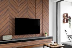 a flat screen tv mounted to the side of a wooden wall in a living room