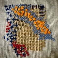 an embroidered piece with orange and blue flowers on it